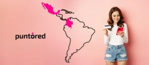 Persona mirando su teléfono móvil junto a un mapa de Latinoamérica que destaca Colombia y México, ilustrando la presencia de Puntored